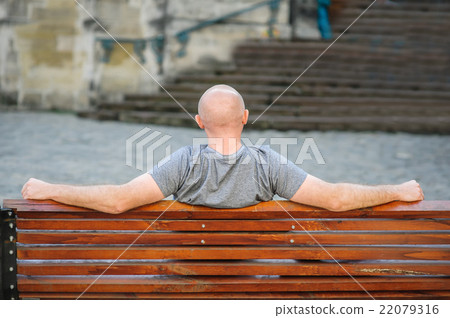 man sits on a bench in city 22079316