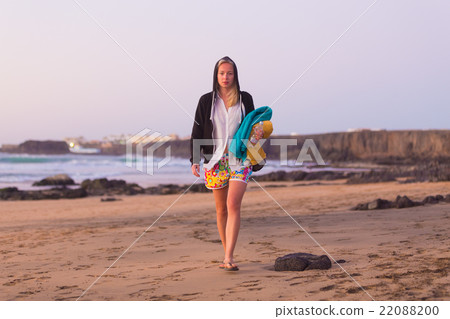Sporty woman walking on sandy beach in sunset. 22088200
