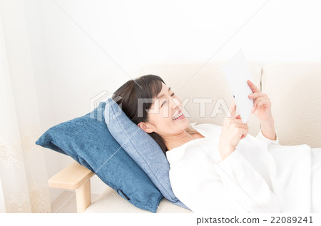 A woman using a tablet while sleeping on a sofa A woman using a tablet while sleeping on a sofa 22089241