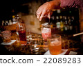 Barman pouring  cocktail into a glass 22089283