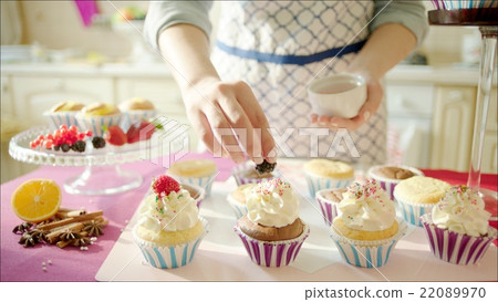 Woman decorating cup-cakes with  sprinkling and 22089970