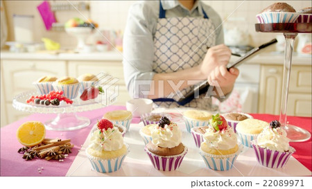 Woman counting cup-cakes sitting at the table 22089971