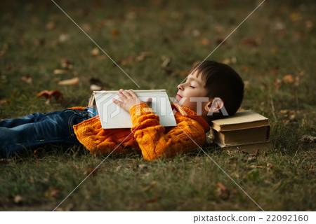 little boy sying on stack of books little boy sying on stack of books 22092160