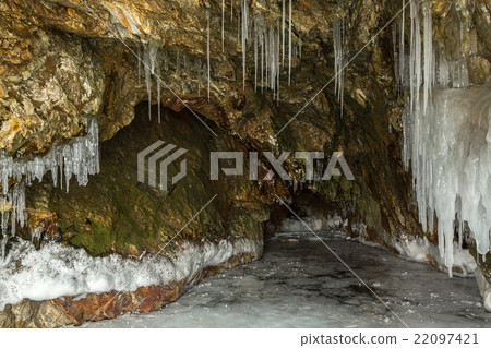 Multicolored stone cave in the cliff with icicles. Multicolored stone cave in the cliff with icicles. 22097421