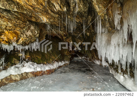 Multicolored stone cave in the cliff with icicles. Multicolored stone cave in the cliff with icicles. 22097462