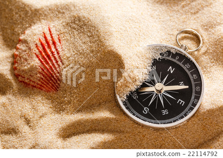 Black compass and sea shell in sand 22114792