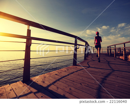 young woman runner running at seaside boardwalk 22116040