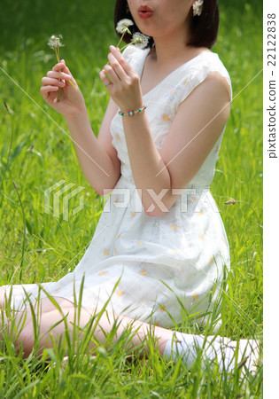 A woman blowing dandelion's fluff A woman blowing dandelion's fluff 22122838