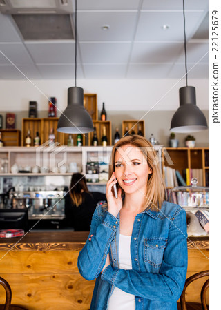 Blond woman standing at the bar, talking on phone 22125679
