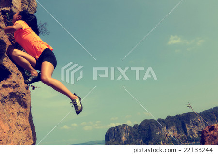 young woman rock climber climbing at seaside young woman rock climber climbing at seaside 22133244