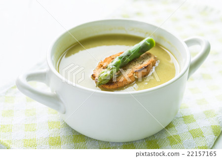 Asparagus soup in a white bowl with slice of bread 22157165