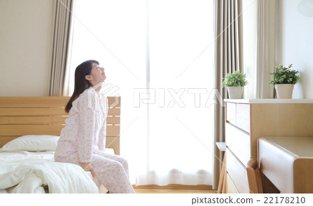 A woman in a pajamas sitting on the bed A woman in a pajamas sitting on the bed 22178210