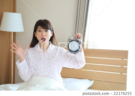 A woman holding an alarm clock and panicking 22178255