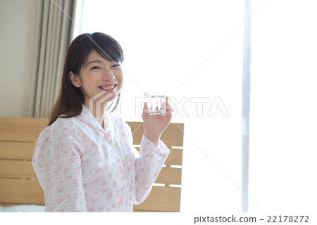 A woman in pajamas who drinks cup water 22178272