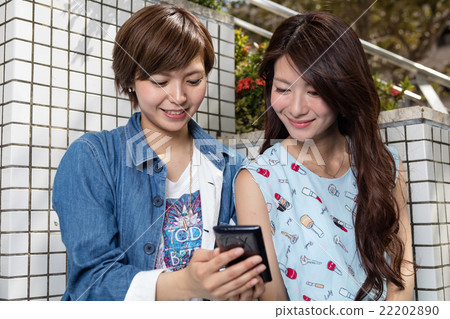 觀看智能手機的兩個人戶外 觀看智能手機的兩個人戶外 22202890