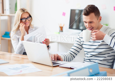 Positive guy drinking coffee at work Positive guy drinking coffee at work 22208083