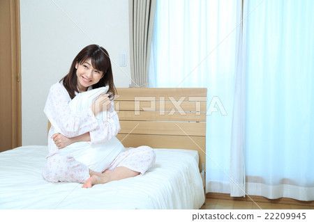 A young woman holding a bed pillow A young woman holding a bed pillow 22209945