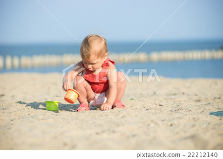 Baby girl in red dress playing on sandy beach near Baby girl in red dress playing on sandy beach near 22212140