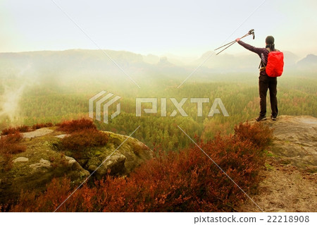 Adult backpacker with poles in the air on rock Adult backpacker with poles in the air on rock 22218908
