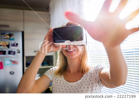 Woman wearing virtual reality goggles standing in 22227199