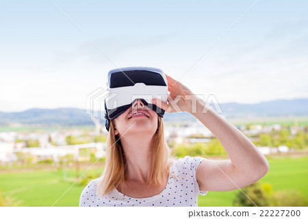 Woman wearing virtual reality goggles standing in 22227200