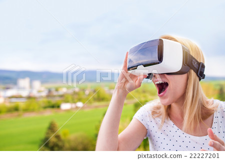 Woman wearing virtual reality goggles standing in 22227201