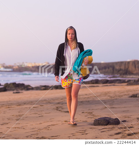 Sporty woman walking on sandy beach in sunset. 22244414