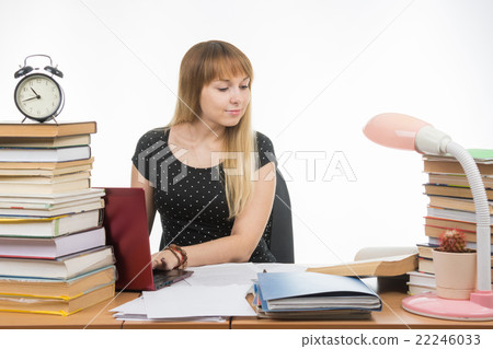 college student smiling with a laptop in gaining information while sitting at a table littered 22246033