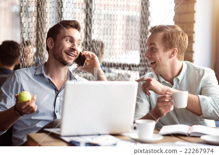Positive smiling  colleagues sitting at the table  22267974
