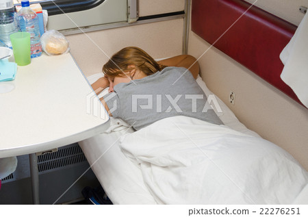 The girl in a train sleeping on his stomach with his hands behind his head on the lower second-class 22276251