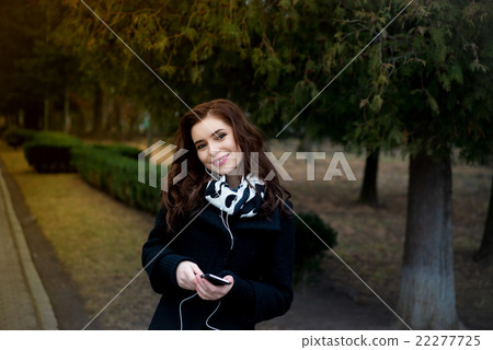 Beautiful girl listens to music in the park 22277725