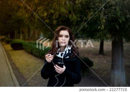 Beautiful girl listens to music in the park 22277728