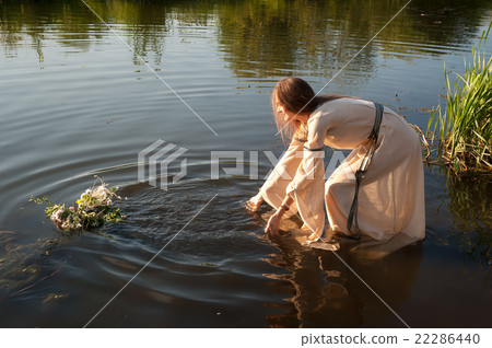 Attractive girl lowers wreath in water Attractive girl lowers wreath in water 22286440