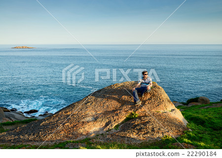 Man sitting on the edge of the rock Man sitting on the edge of the rock 22290184