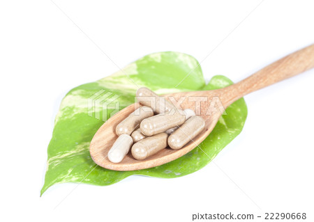 Capsules of herbs on spoon on white background Capsules of herbs on spoon on white background 22290668