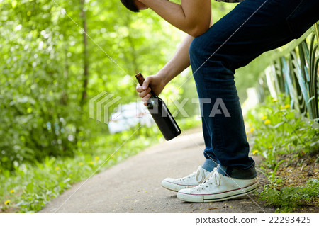 Man depressed with beer bottle sitting on green Man depressed with beer bottle sitting on green 22293425