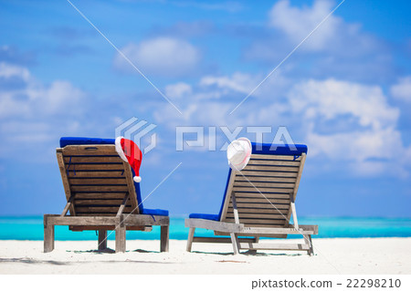 Red santa hat and white straw hat on sunlongue at Red santa hat and white straw hat on sunlongue at 22298210