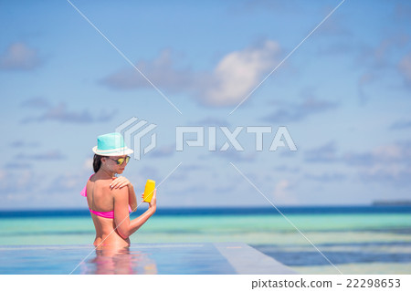 Young woman applying sun cream during beach Young woman applying sun cream during beach 22298653