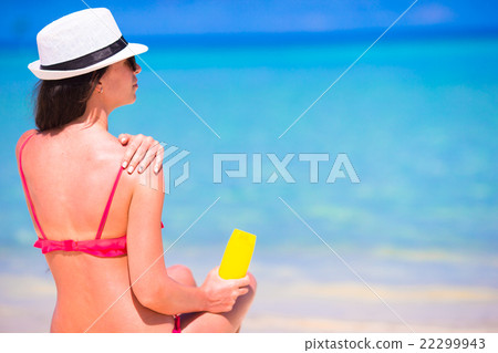 Beautiful young woman holding a suncream lying on Beautiful young woman holding a suncream lying on 22299943
