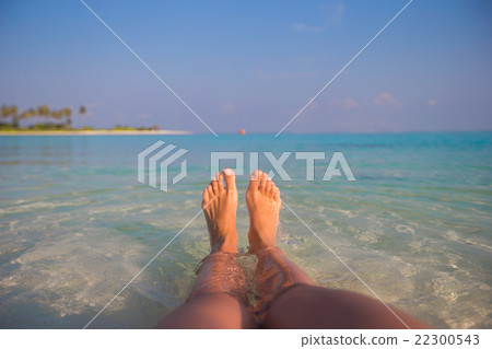 Female feet on white sandy beach and clear water 22300543