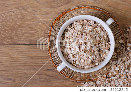 Oat flakes in a bowl and scattered on the table 22312845