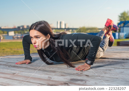 Fit woman doing knee push-ups working out outdoors 22328207