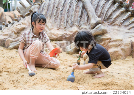Little asian children has fun digging in the sand Little asian children has fun digging in the sand 22334034