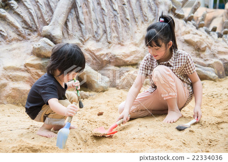 Little asian children has fun digging in the sand Little asian children has fun digging in the sand 22334036