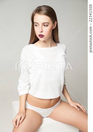 Portrait of brunette in undies sitting on cube 22341508