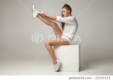 Young woman putting on sneakers 22341513