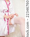Bride putting a wedding garter on her leg 22346760