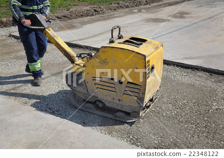 Worker use vibratory plate compactor at road 22348122