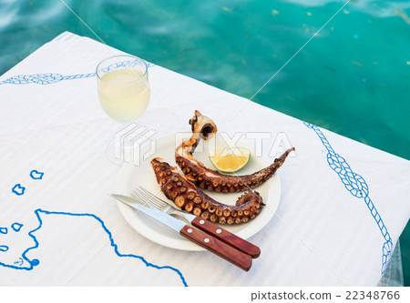 Grilled octopus and white wine glass on a table at 22348766