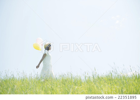 A woman holding a balloon in the meadow and smiling 22351895